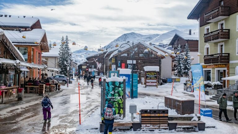 Rue commerçante enneigée d'une station de ski avec boutiques et terrasses